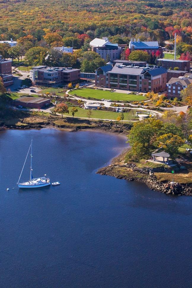 Aerial view of brick buildings surrounded by trees and next to a river